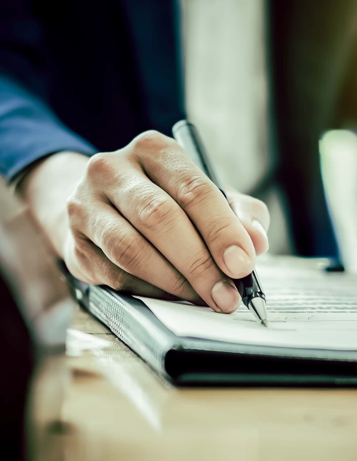 A close-up of a hand with a pen reviewing a document.