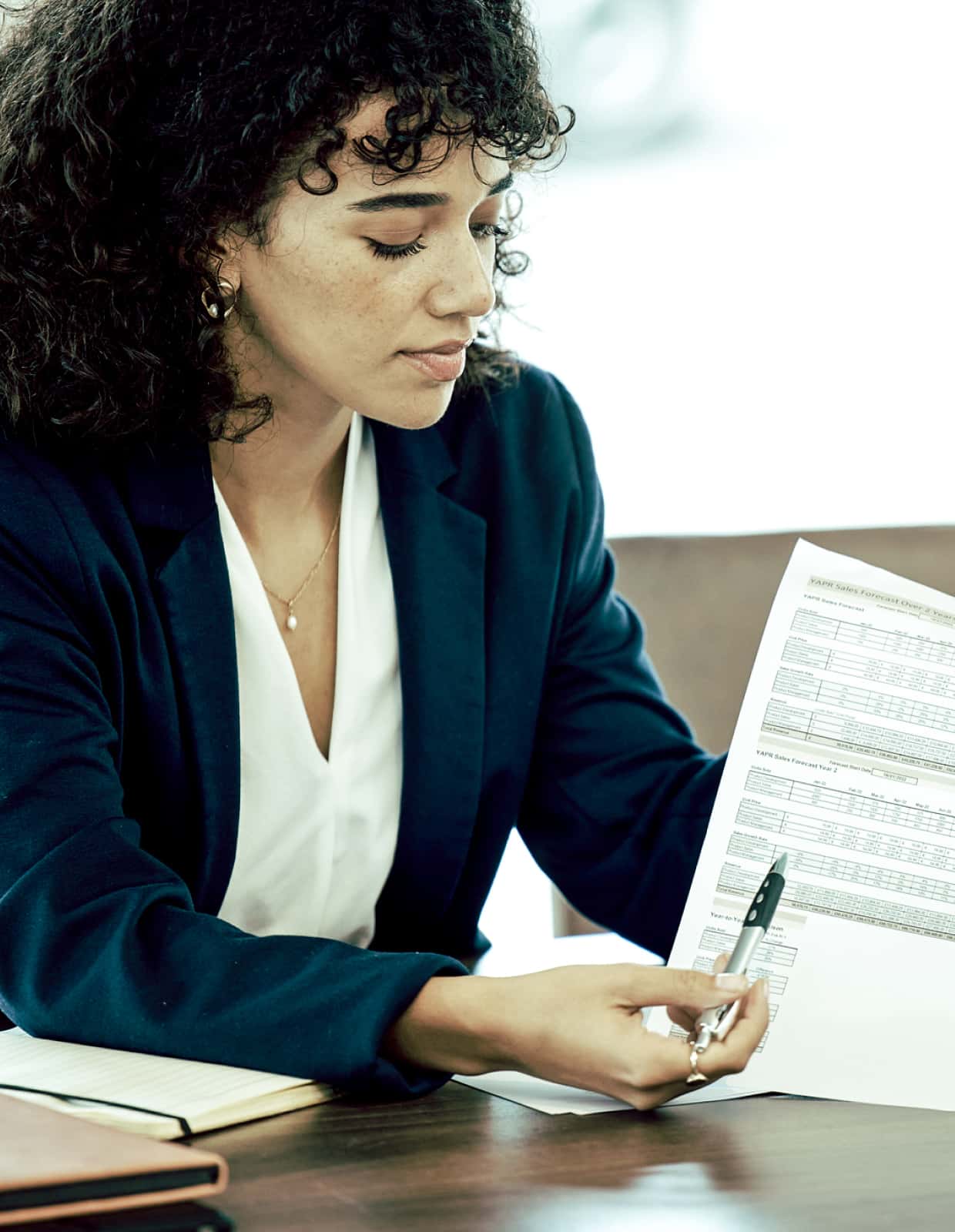A woman in a blazer reviews paperwork.