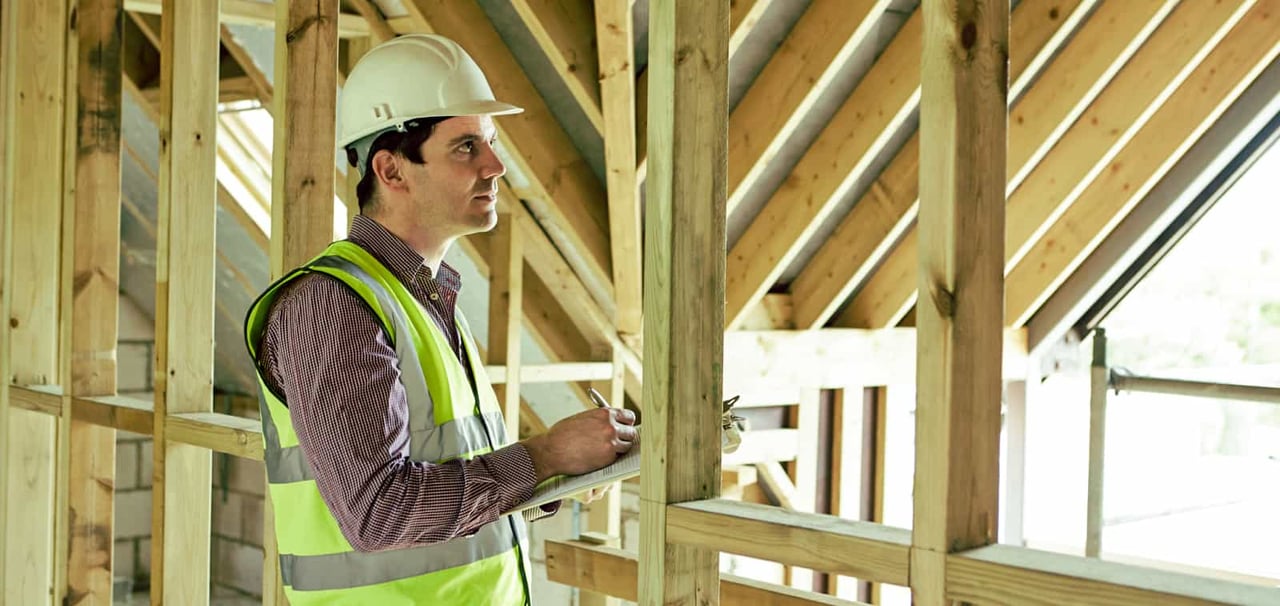 Construction worker looking through site with clipboard. 